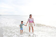 © zilvergolf - Happy Asian mom and son enjoy playing on tropical sand beach at sunrise. Happy family in summer holiday.