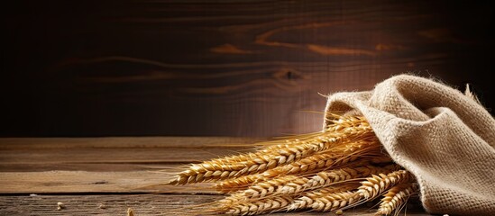 Canvas Print - Wheat stalks and sack of grains on wooden surface