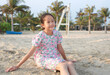 Portrait of smiling Asian young girl child lying on beach sand at summer holiday.