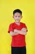 Portrait Asian little boy age about 7 years old standing and cross arms over chest looking straight at camera on yellow studio background.