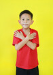 Smiling Asian boy child in red casual crossed arm and looking camera isolated on yellow background. Confident and cheerful kid.
