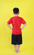 Back view of Asian little boy child stand akimbo posture isolated on yellow background. Image full length.
