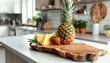Wooden board with cut pineapple on table in kitchen