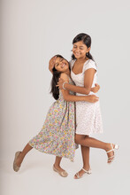 Two Young Girls Hug Each Other In A White And Floral Dress