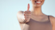 Woman, hand and fitness with thumbs up for winning, thank you or success on a blue sky background. Closeup of female person or athlete with like emoji, yes sign or ok for approval, review or feedback