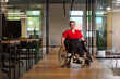 © .shock - A modern young businesswoman in a wheelchair is surrounded by an inclusive workspace with glass-walled offices, embodying determination and innovation in the business world