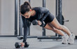 Woman, push up and dumbbell in gym for workout, exercise and training for strong abs or muscle. Female person, bodybuilder and athlete for sport and plank, power core and equipment for weightlifting