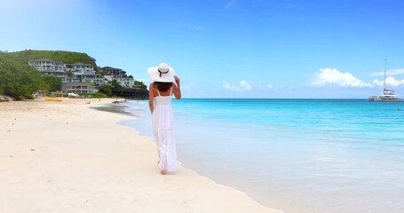 Sticker - A elegant woman in a white summer dress walks along the beautiful Darkwood beach at the Caribbean island of Antigua