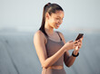 Outdoor, exercise and woman with smartphone, hands and social media with fitness, check progress and wellness. Blue sky, person or runner with cellphone, closeup or typing with digital app or network