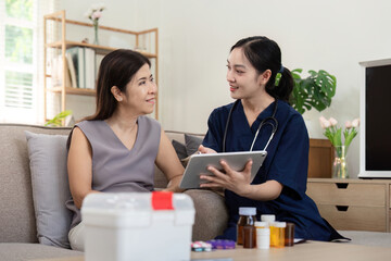 Female caregiver showing medical test result explaining prescription using digital tablet app visit senior woman patient at home sitting on sofa. Elderly people healthcare tech concept