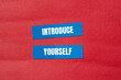 © Emre Akkoyun - Introduce yourself words written on blue paper stickers with red background. Conceptual introduce yourself symbol. Copy space.