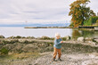 Outdoor portrait of happy and active toddler boy playing by the lake on a nice spring or autumn day