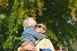 Outdoor portrait of adorable toddler boy giving a hug and kiss to his lovely mom, happy family life