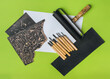 Linocut tools. Cutters, roller, black linoleum and white sheet of paper on a green background. Handicraft and design concept. Handmade creativity.
