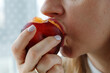 Close-up of a woman's mouth eating ripe peach a lunchtime, a healthy fresh snack for healthy people.