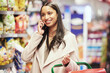 Woman, phone call and groceries with smile, planning and discussion for dinner in supermarket. Customer, shopping and retail with cellphone, conversation and communication for discount or purchase