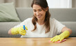 Woman, cleaning and wood in home with smile for housework, spray and cloth for furniture. Female cleaner, or table with container and soap for washing, hospitality service in house or apartment