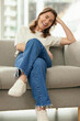 Funny, smile and woman on sofa in home living room for relax, comedy or joke in apartment in Switzerland. Laughing, comic and happy girl on couch for comfort or excited in casual clothes in lounge