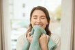 Happy, woman and smelling clean towel with fresh fabric after doing laundry for spring cleaning at home. Female person and smile for detergent scent or fragrance from routine house maintenance