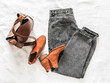 Women's grey mom jeans, brown leather tote bag, suede chelsea boots on a light background, top view