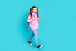 Full length photo of lovely little girl backpack walking dressed stylish pink garment isolated on aquamarine color background