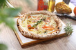 Crispy Italian pizza with cheese, smoked salmon, onion, rosemary, on a wooden cutting board, top view, selective focus.