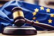 photograph showcasing the intricate details of a judge's wooden gavel, with the EU flag prominently displayed in the background, representing the harmonization of legal principles