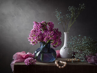 Wall Mural - A bouquet of bergenia in a light vase on a dark background. Modern still life with flowers