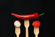 Red pepper, tomato and radish on wooden disposable forks, close-up, dark background. Healthy eating concept. Fresh vegetables in the diet. Vegetables on a black background. Space for text