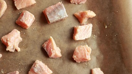 Wall Mural - Close-up of raw fresh salmon fillets cut into cubes and arranged on parchment paper in a tray, ready for cooking, showcasing their quality and freshness