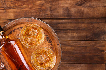 Canvas Print - Whiskey with ice cubes in glasses, bottle and barrel on wooden table, top view. Space for text