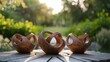 Three brown wooden sculptures on a table outside, with a blurred background of trees and sunlight.