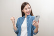 Happy with phone asian young woman, girl holding mobile smart phone, read good news winning feel excited getting offer, great positive surprise, celebrate success on smartphone isolated on background.