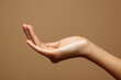 © Anna - Close up of woman hand with palm facing upwards isolated on brown background. Female hand showing empty hand. Woman holding your beauty product