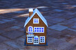 Toy two-story house with blue light in the windows against the background of paving slabs