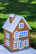 Toy two-story house with blue light in the windows on a background of green grass
