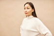 Studio side view portrait of pretty curious asian female looking at copy space reading tips or advice helping to find job and achieve goals standing against pink background in mockup turtleneck