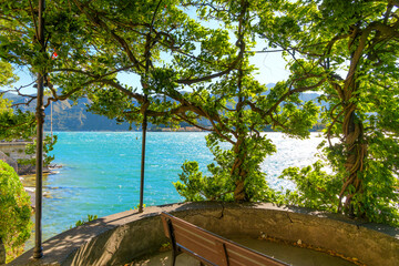 Wall Mural - View from a lush plant covered lakefront promenade terrace overlooking the lake at the Italian resort town of Tremezzina, Italy, on the shores of Lake Como.