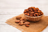 Fototapeta Na sufit - Almonds in Wicker Basket Bowl on White Wooden Table. Almond Concept with Copy Space