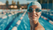 portrait of a happy woman in swimming goggles and a rubber cap looks into the frame with a smile in front of the swimming lanes of an outdoor pool