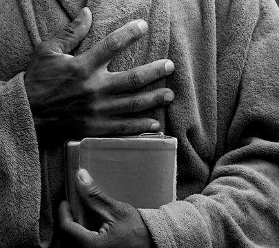 man praying to god with hands together on dark background stock photo	