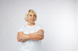 Beautiful senior blonde 60s woman smiling and looking at camera over white background. Human emotions, facial expression concept