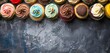Top view of tasty colourful cupcakes on dark grunge background with copy space for text.