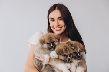 Portrait of happy smiling millennial woman holding Akita Inu puppies on white background