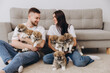 © anatoliycherkas - Beautiful smiling happy couple playing with akita inu puppies in dog house or shelter