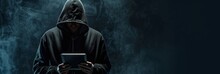 A Hacker In A Black Hoodie With The Hood Up Holding A Tablet Computer Isolated On A Dark Background, In The Style Of Copy Space Concept Generative AI
