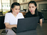 Fototapeta Koty - Asian women co-workers in workplace including person with blindness disability using laptop computer with screen reader program for visual impairment people. Disability inclusion at work concepts
