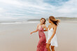 multiracial couple of female friends hugging and happily strolling along the beach in summer. Summer trip