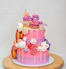 Wall Mural - Pink ombre birthday cake with donuts, meringues and chocolate on neutral background. Cupcake on the top