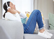 Headphones, music and woman on sofa in home for relaxing, resting and chill on weekend. Happy, smile and person on couch listening to audio, song and radio on streaming subscription in living room